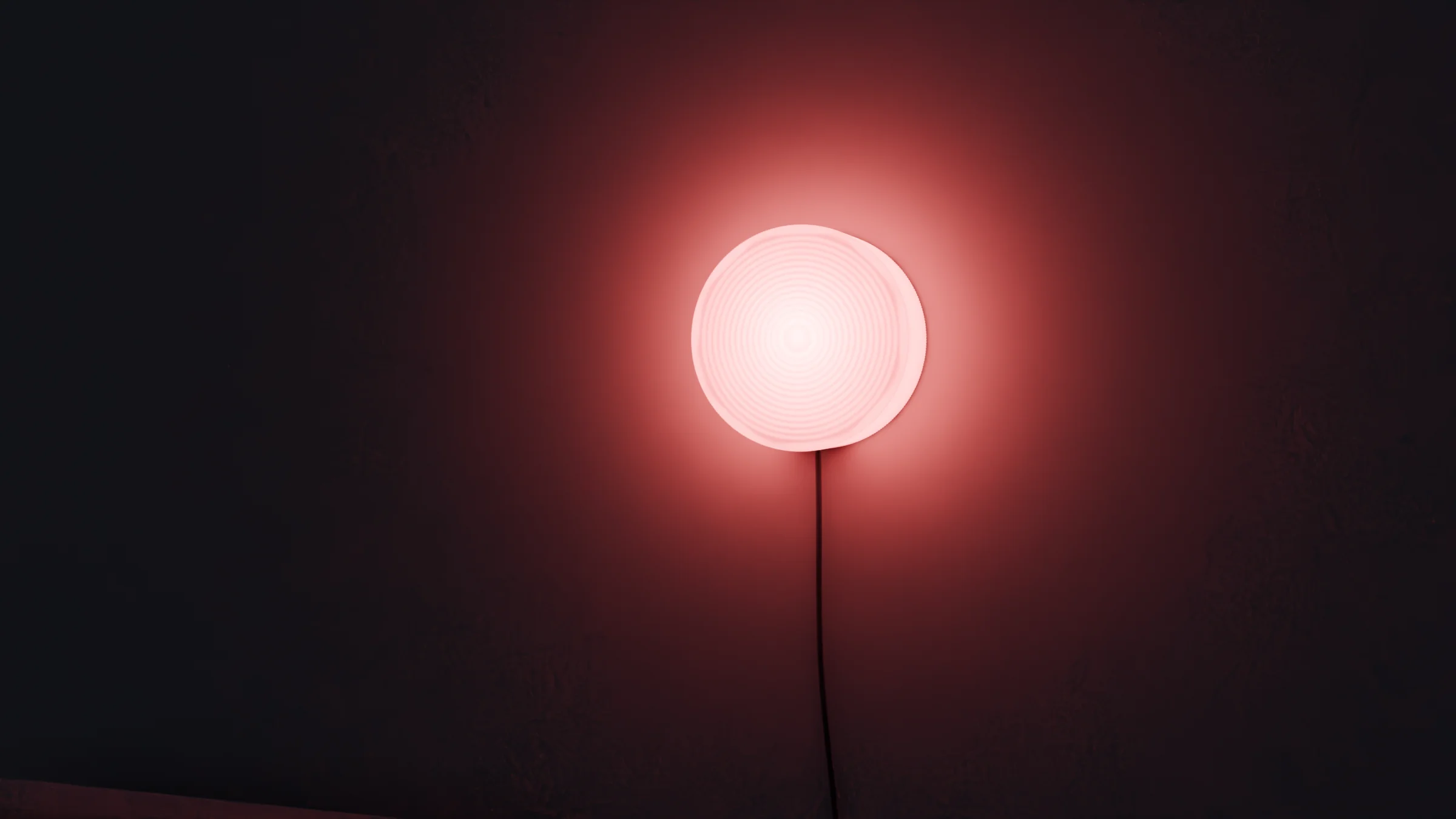 Maru plug-in wall light glowing pink on a dark wall